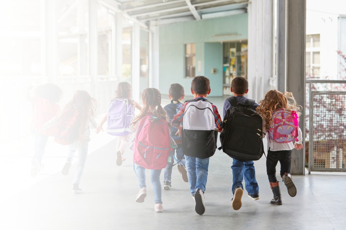Grundschüler laufen durch einen Schulkorridor.