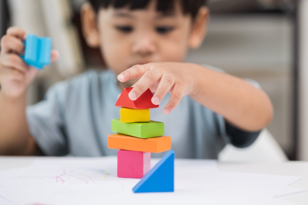 Junge stapelt Bauklötze auf einem Tisch